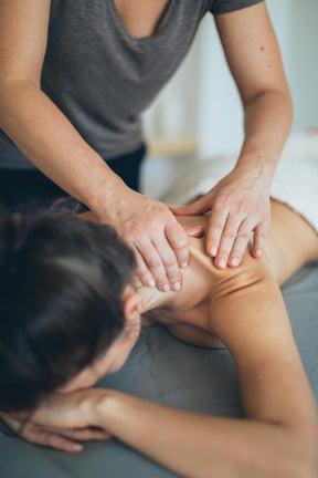 Woman receiving a massage with Koy CBD muscle and joint relief balm, featuring organic jojoba, cayenne, and peppermint for pain relief and relaxation